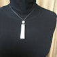 Adjustable short aluminum necklace with long rectangle pendant.